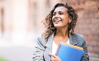 girl smiling with big hoop earings looking left, holding blue spiral notebook