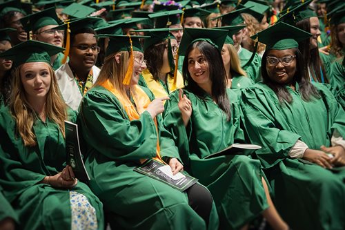 graduates in green regalia talking